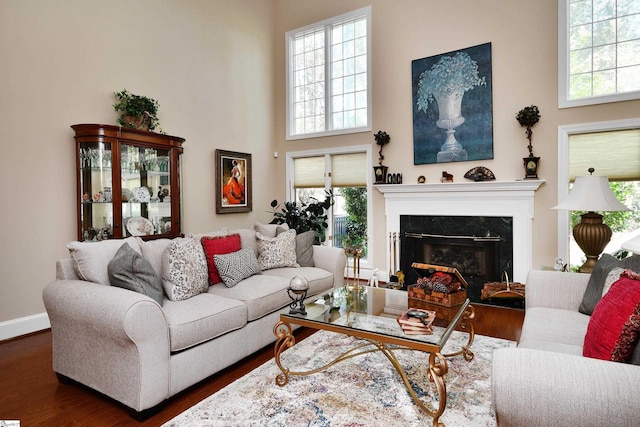 living room with a high end fireplace, a towering ceiling, and dark hardwood / wood-style floors