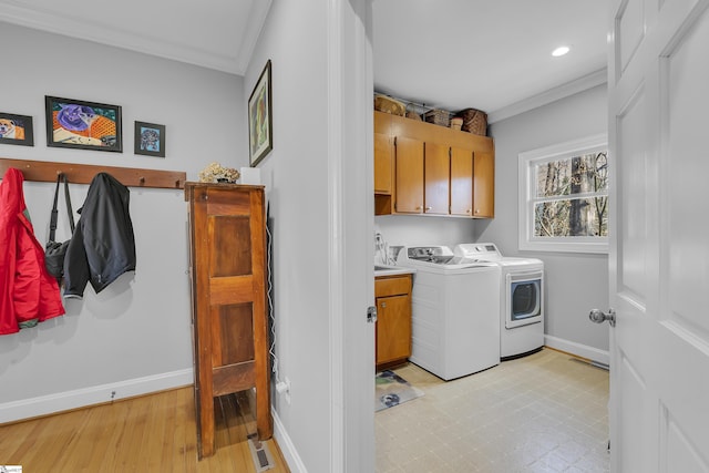 clothes washing area with independent washer and dryer, crown molding, and cabinets