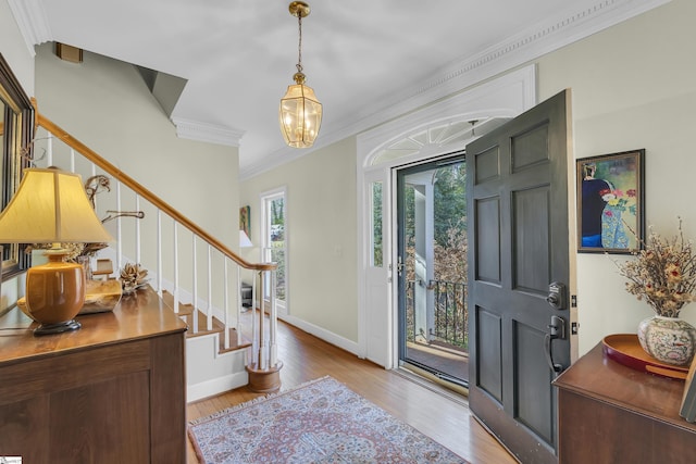 entryway with light hardwood / wood-style floors, a chandelier, and crown molding