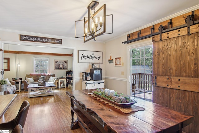 dining room with a notable chandelier, ornamental molding, plenty of natural light, and hardwood / wood-style floors