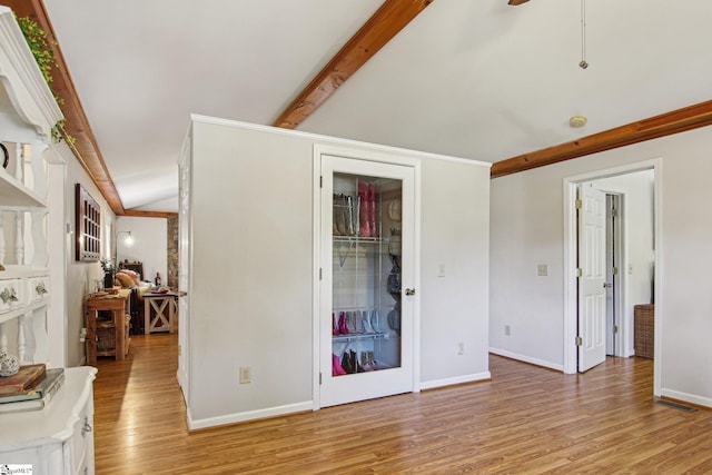 bedroom with light wood-type flooring and vaulted ceiling with beams