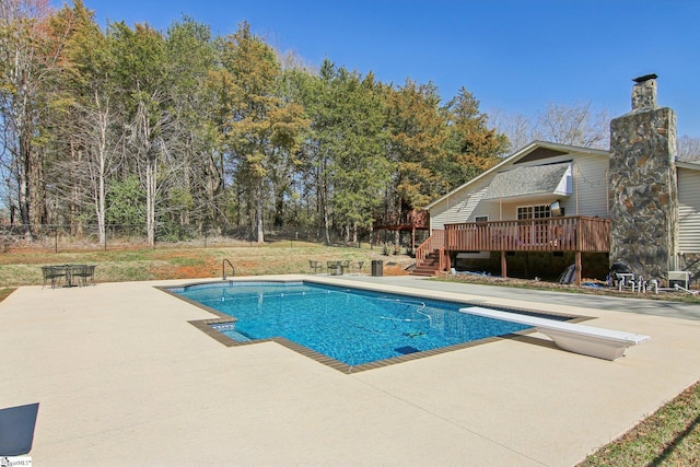 view of swimming pool featuring a deck, a patio, and a diving board