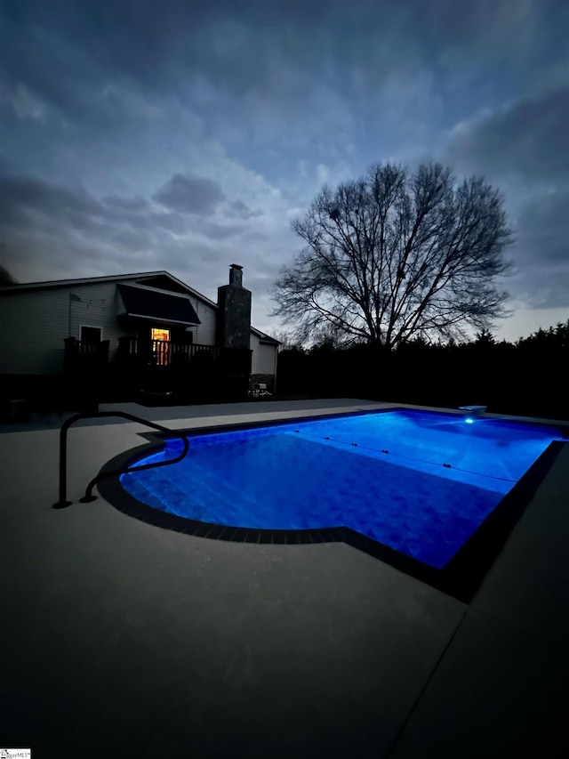 pool at dusk with a patio area