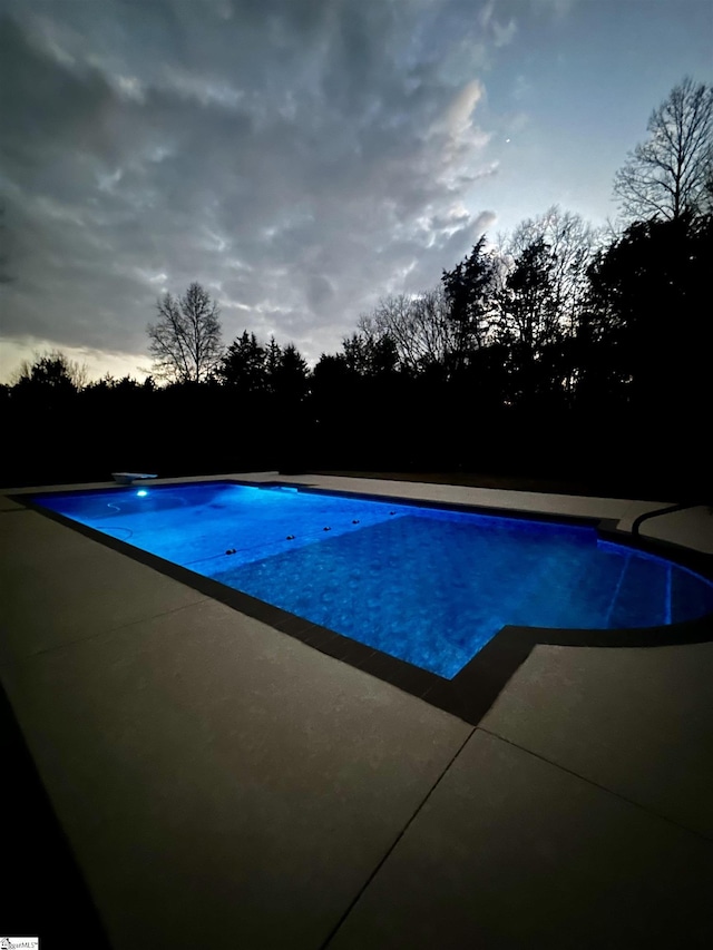 pool at dusk with a patio area