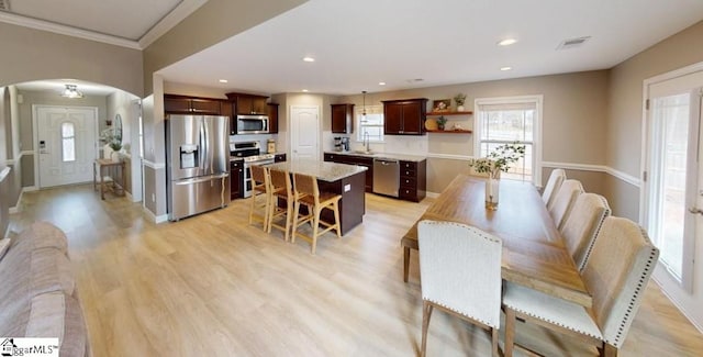 dining room featuring light wood-type flooring, sink, and crown molding