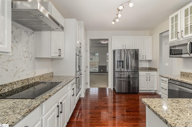 kitchen featuring white cabinetry, light stone countertops, tasteful backsplash, appliances with stainless steel finishes, and wall chimney range hood