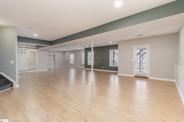 unfurnished living room with light hardwood / wood-style flooring and a barn door