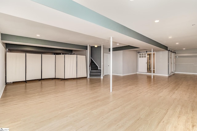 basement with light hardwood / wood-style flooring and a barn door