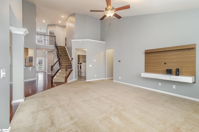 carpeted living room with ceiling fan, washer and dryer, and a high ceiling