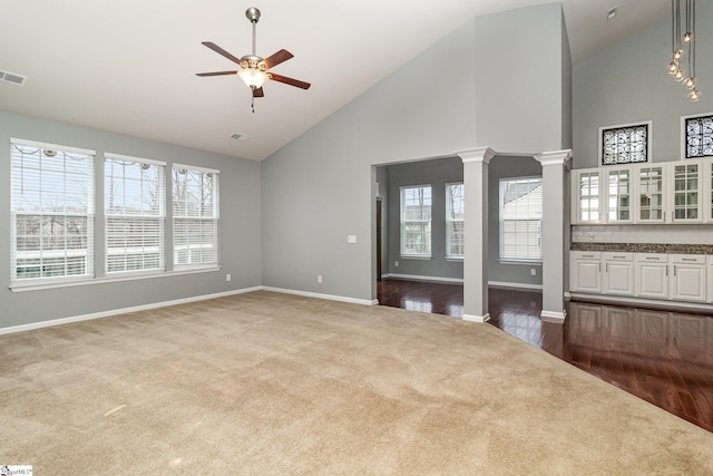 unfurnished living room featuring light carpet, plenty of natural light, ceiling fan, and decorative columns