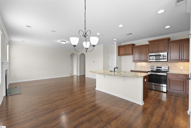 kitchen with an island with sink, stainless steel appliances, decorative light fixtures, sink, and a kitchen breakfast bar