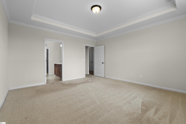 unfurnished bedroom with ornamental molding, light colored carpet, ensuite bath, and a raised ceiling