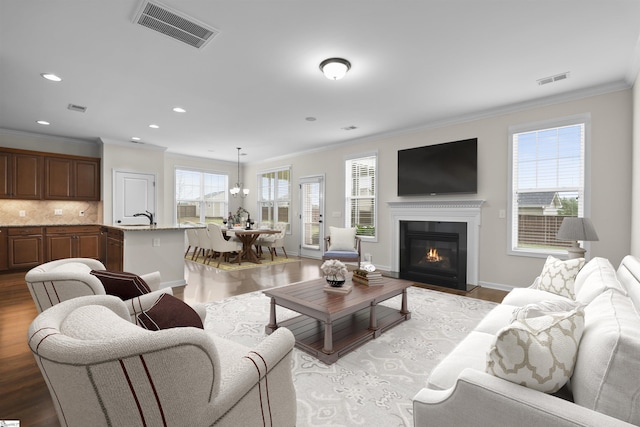 living room featuring sink, light wood-type flooring, and crown molding