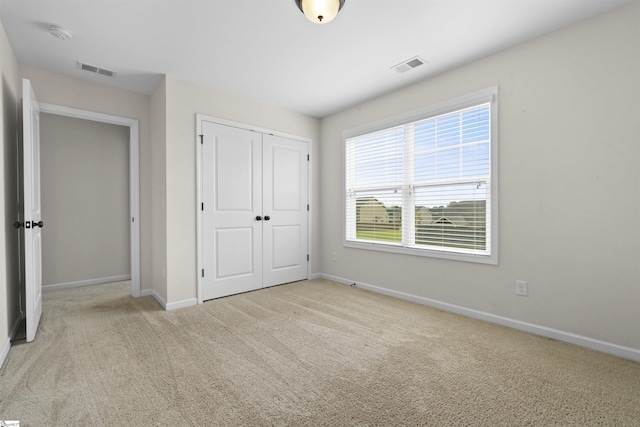 unfurnished bedroom featuring light carpet and a closet