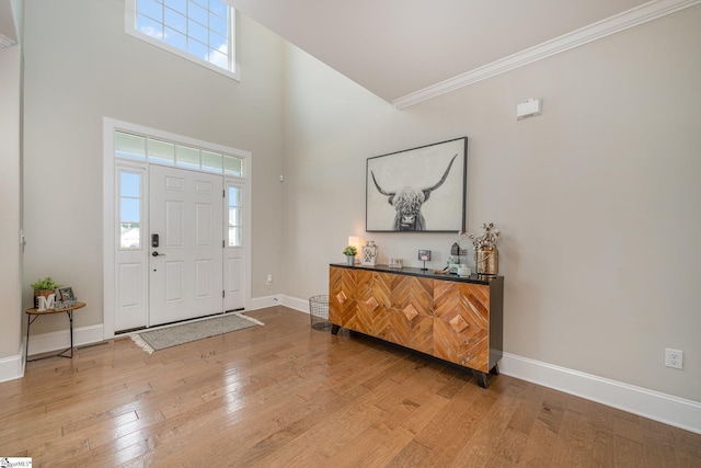 entrance foyer with a high ceiling, ornamental molding, and hardwood / wood-style floors