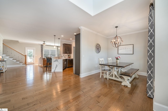 dining area with ceiling fan with notable chandelier, light wood-type flooring, and crown molding