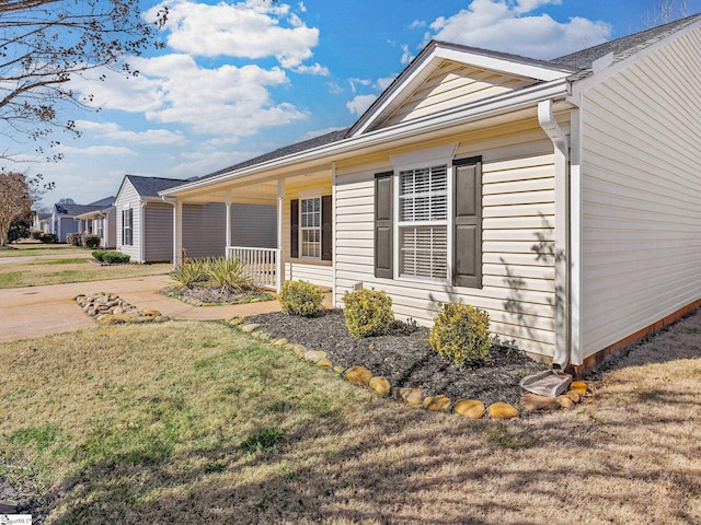 view of side of home with covered porch and a lawn