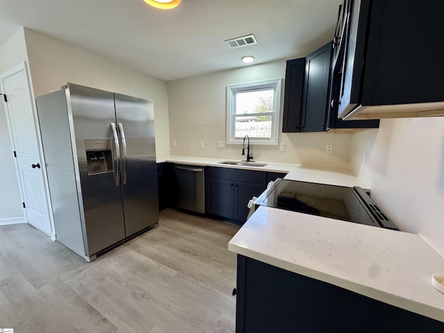 kitchen with light wood-type flooring, appliances with stainless steel finishes, and sink