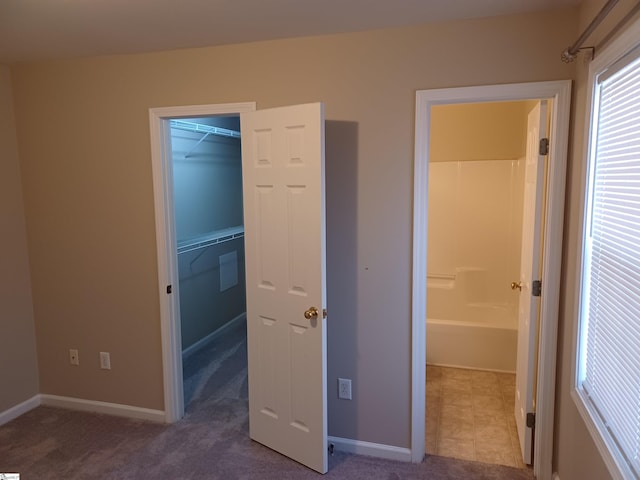 unfurnished bedroom featuring dark carpet, a closet, and a spacious closet