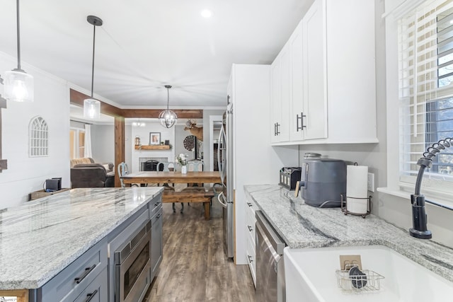 kitchen with white cabinetry, hanging light fixtures, light stone countertops, and stainless steel appliances