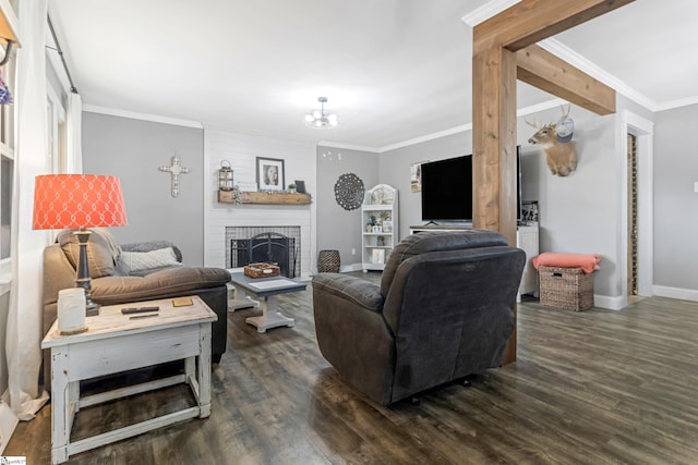 living room with dark wood-type flooring, crown molding, a brick fireplace, and an inviting chandelier