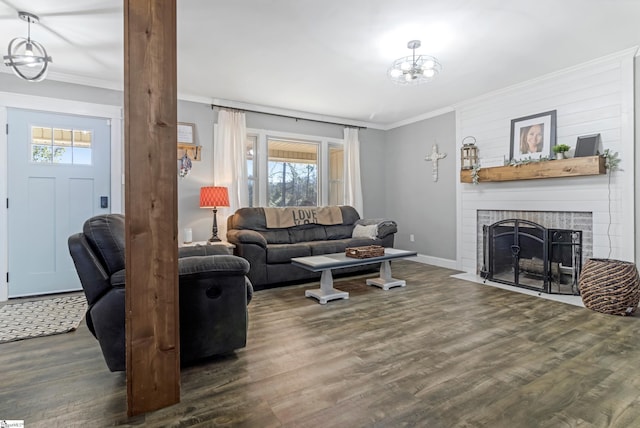 living room featuring a notable chandelier, ornamental molding, dark hardwood / wood-style floors, and a fireplace