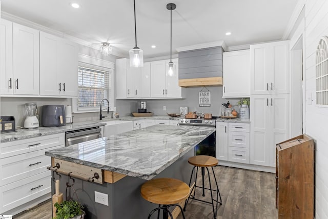 kitchen with appliances with stainless steel finishes, a kitchen island, and white cabinets