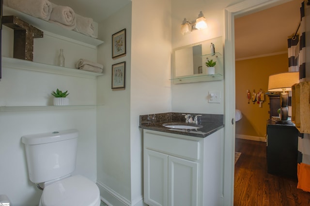 bathroom featuring toilet, hardwood / wood-style flooring, vanity, and ornamental molding