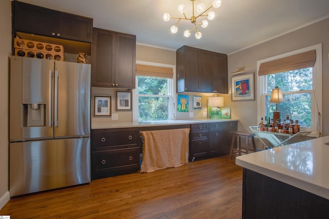 kitchen with stainless steel fridge, a notable chandelier, ornamental molding, dark brown cabinets, and wood-type flooring