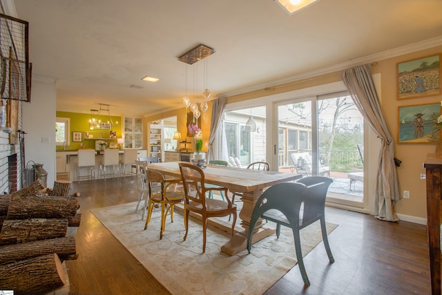 dining room with a brick fireplace, crown molding, hardwood / wood-style floors, and a healthy amount of sunlight