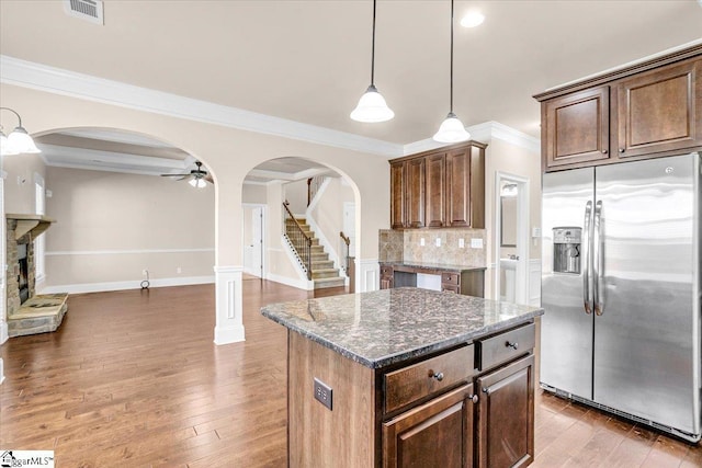 kitchen featuring dark stone counters, hardwood / wood-style floors, a center island, and stainless steel refrigerator with ice dispenser