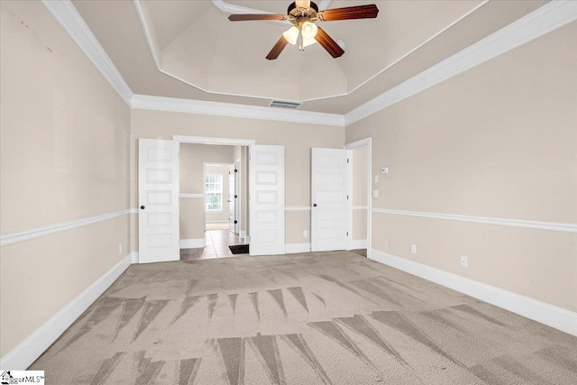 unfurnished bedroom featuring a tray ceiling, ornamental molding, light carpet, and ceiling fan