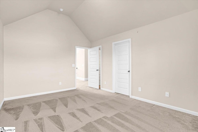 unfurnished bedroom with light colored carpet and lofted ceiling