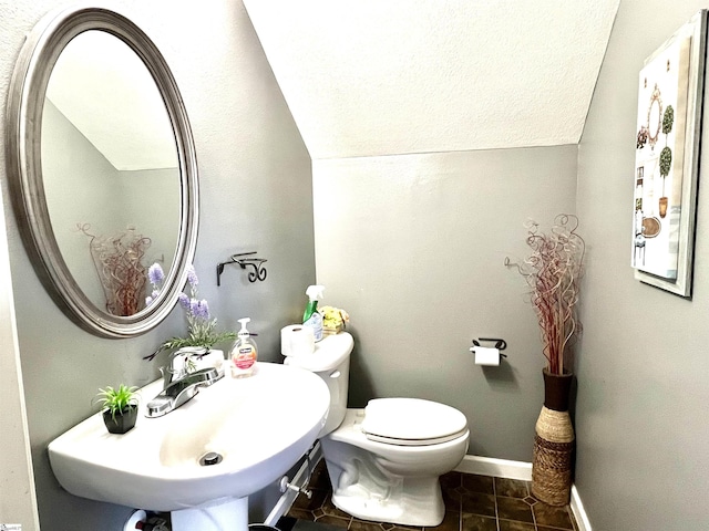 bathroom featuring sink, toilet, lofted ceiling, and tile patterned floors