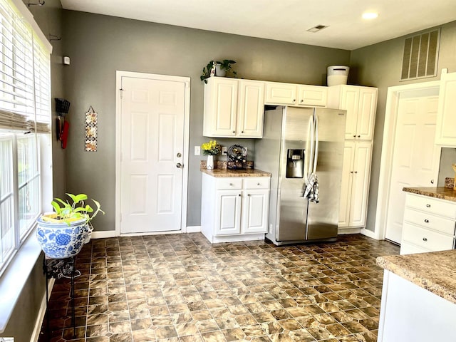 kitchen with white cabinets, stainless steel fridge with ice dispenser, baseboards, and visible vents