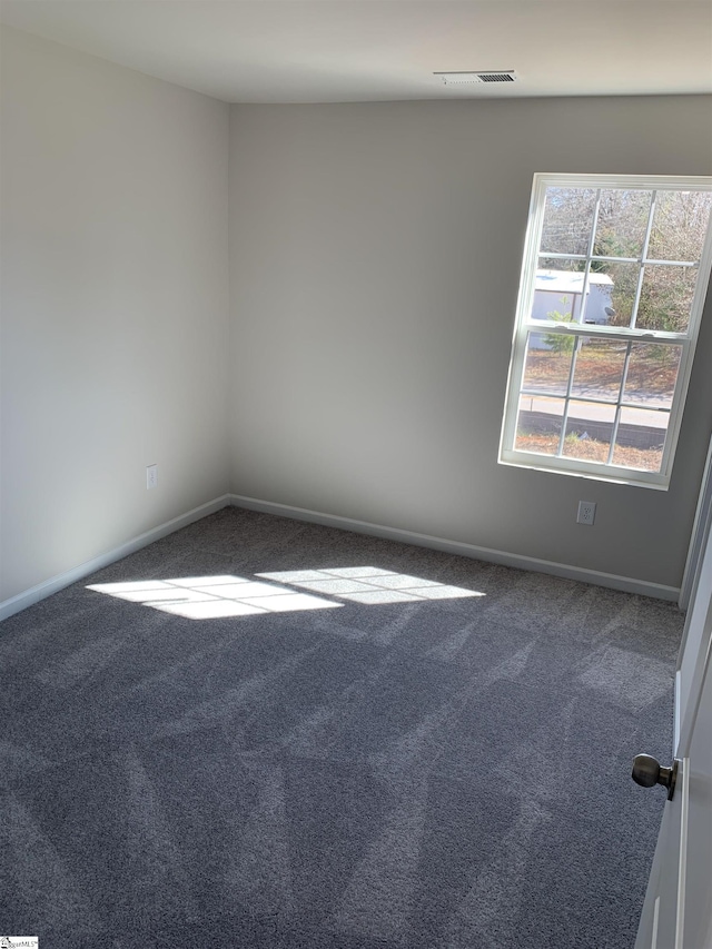 carpeted spare room featuring baseboards and visible vents