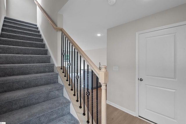 staircase with baseboards, wood finished floors, and recessed lighting