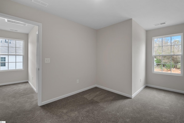 unfurnished room featuring dark carpet and visible vents