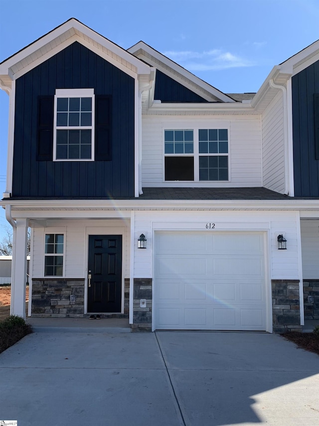 view of front facade featuring board and batten siding, concrete driveway, stone siding, and an attached garage