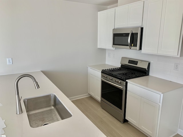 kitchen featuring white cabinetry, light countertops, decorative backsplash, and appliances with stainless steel finishes