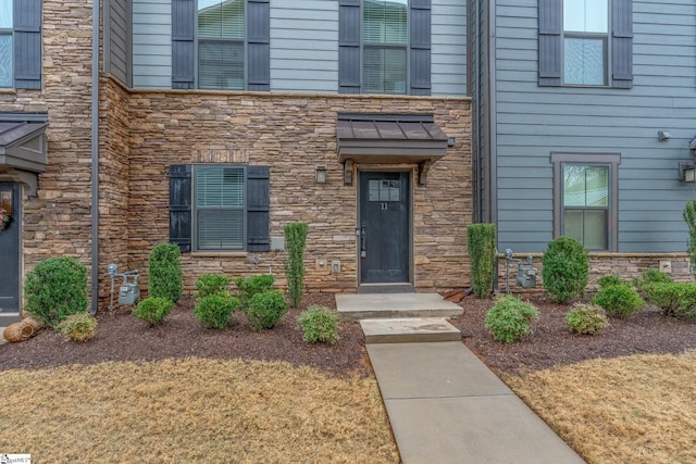 entrance to property featuring a yard and stone siding