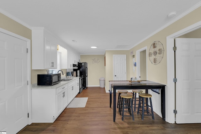 kitchen with sink, black appliances, white cabinets, and dark hardwood / wood-style flooring