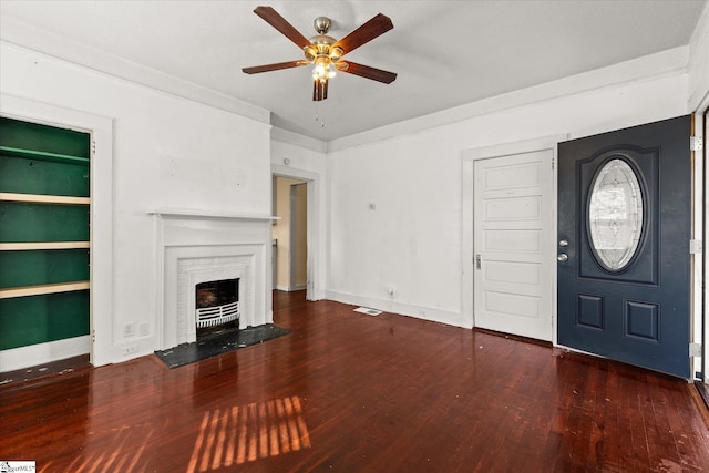 foyer featuring dark hardwood / wood-style flooring, ceiling fan, crown molding, and a brick fireplace