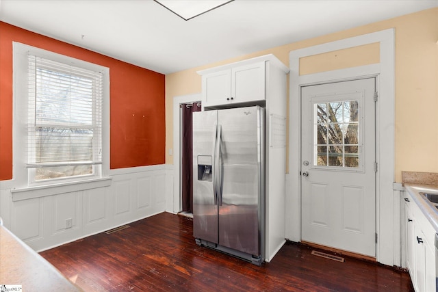 kitchen with dark wood-type flooring, white cabinets, stainless steel fridge with ice dispenser, and plenty of natural light