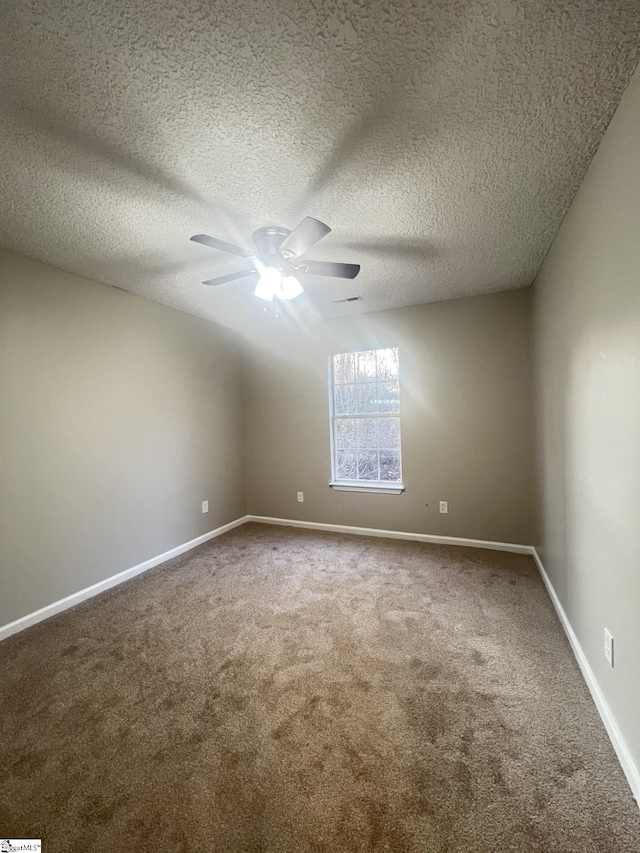 carpeted empty room with ceiling fan and a textured ceiling