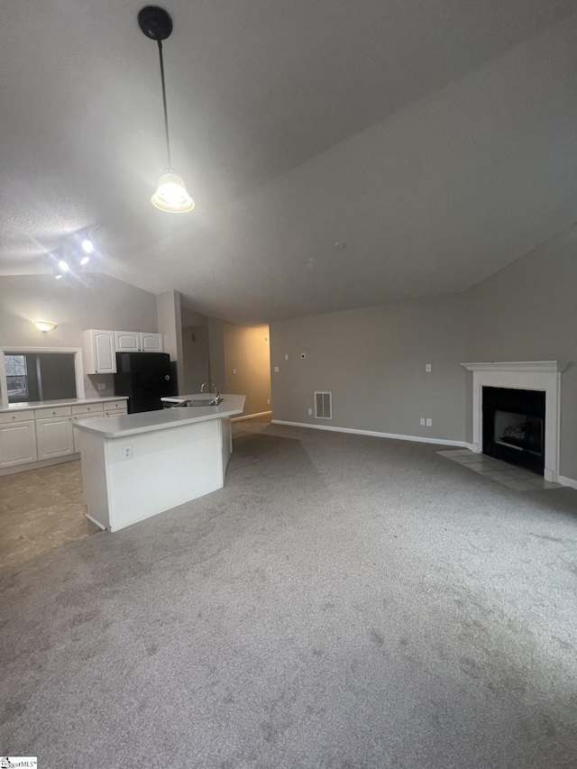 kitchen featuring vaulted ceiling, a center island, white cabinetry, pendant lighting, and black refrigerator