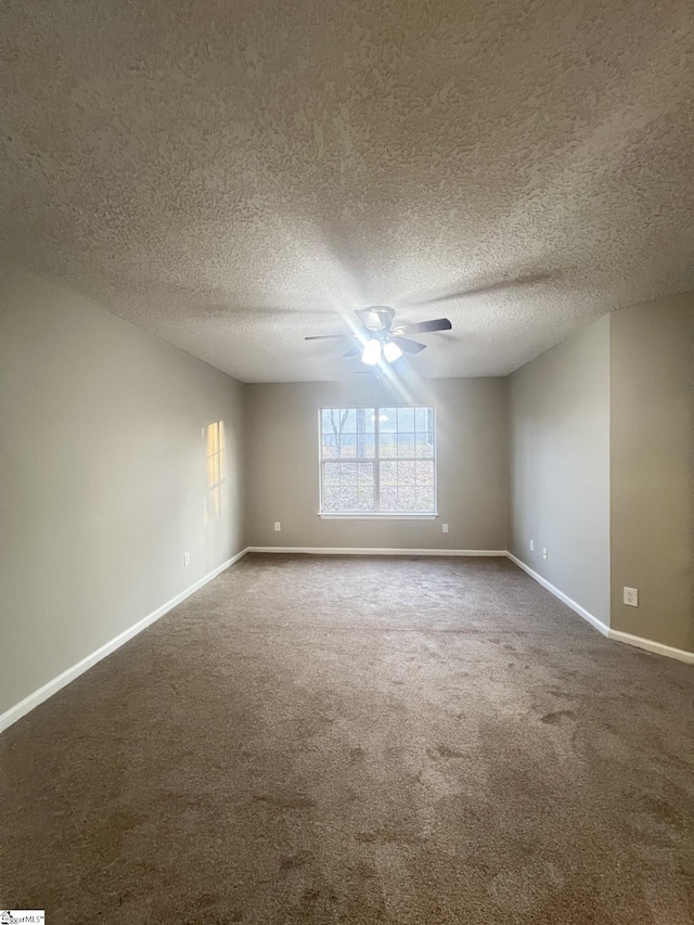 spare room featuring dark carpet, ceiling fan, and a textured ceiling