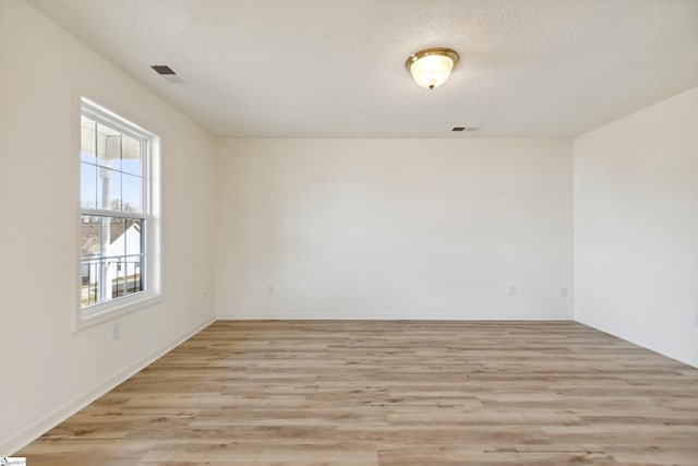 empty room featuring light wood-type flooring and a textured ceiling