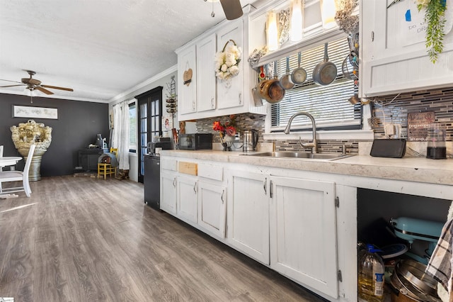 kitchen with hardwood / wood-style floors, ceiling fan, white cabinetry, and sink