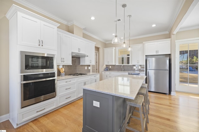 kitchen featuring white cabinets, appliances with stainless steel finishes, a kitchen island, and pendant lighting